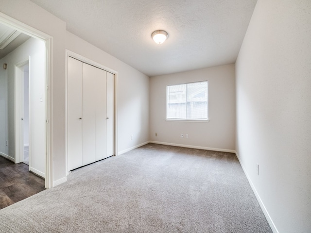 unfurnished bedroom with a closet, dark carpet, and a textured ceiling