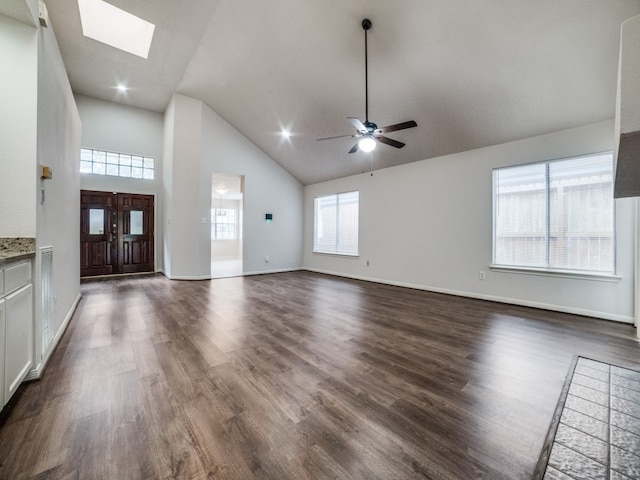 unfurnished living room with high vaulted ceiling, dark hardwood / wood-style flooring, a skylight, and ceiling fan