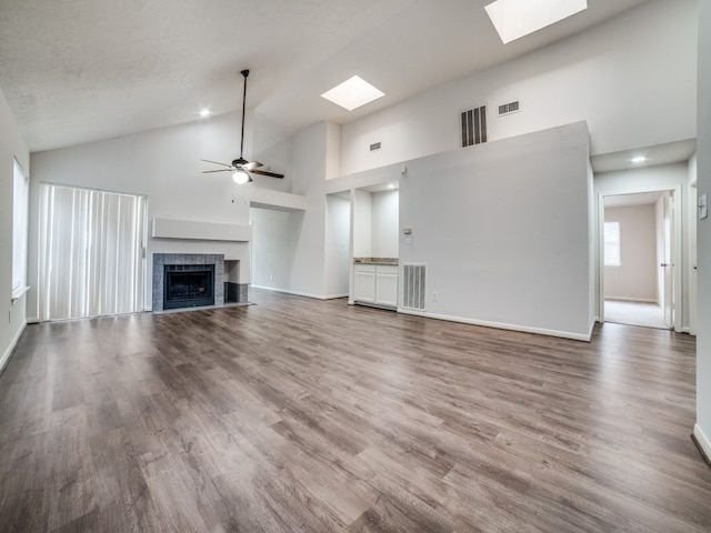 unfurnished living room with ceiling fan, a fireplace, hardwood / wood-style floors, and high vaulted ceiling