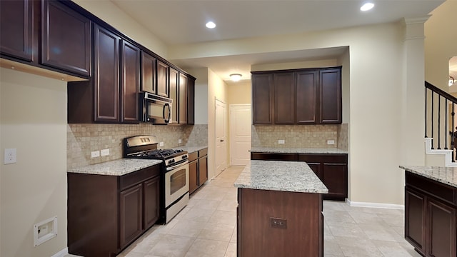 kitchen featuring dark brown cabinetry, stainless steel range with gas cooktop, a kitchen island, and light stone counters