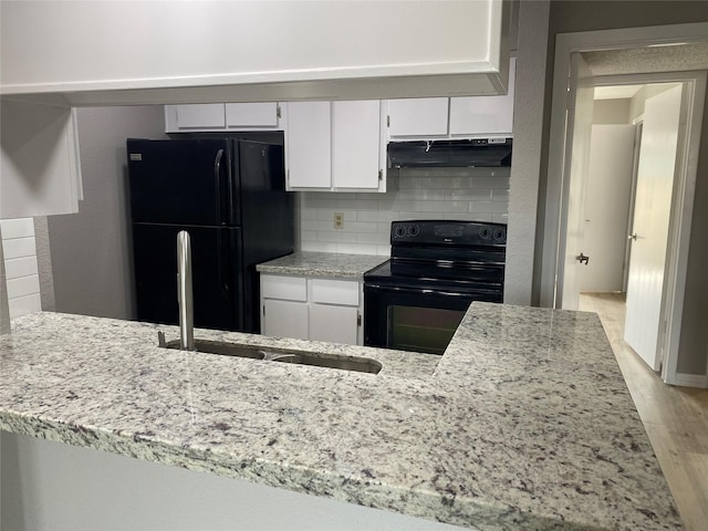 kitchen featuring backsplash, sink, black appliances, light hardwood / wood-style floors, and white cabinetry