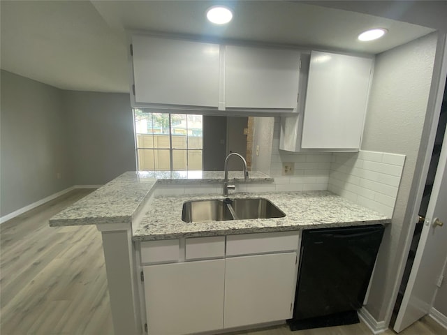 kitchen featuring white cabinets, sink, light stone countertops, black dishwasher, and kitchen peninsula