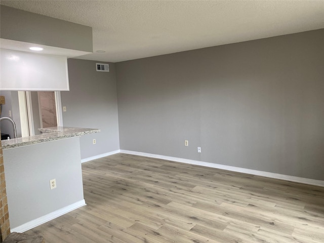 unfurnished living room featuring a textured ceiling and light wood-type flooring