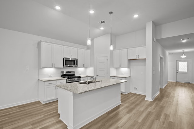 kitchen with sink, white cabinetry, stainless steel appliances, and an island with sink