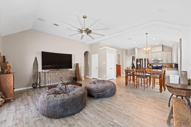 living room with lofted ceiling, light hardwood / wood-style floors, and ceiling fan with notable chandelier