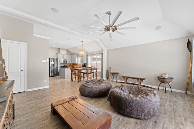 living room with ceiling fan with notable chandelier, light hardwood / wood-style floors, and lofted ceiling