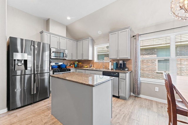 kitchen with sink, a healthy amount of sunlight, stainless steel appliances, a kitchen island, and light wood-type flooring