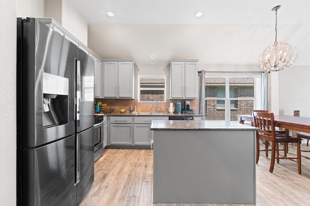 kitchen with a center island, pendant lighting, gray cabinets, appliances with stainless steel finishes, and light wood-type flooring