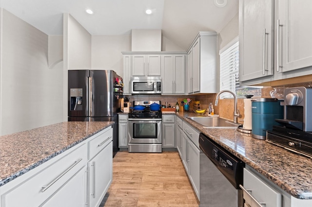 kitchen featuring decorative backsplash, stainless steel appliances, sink, stone countertops, and lofted ceiling