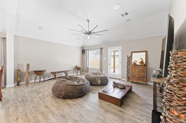 living room featuring ceiling fan, light hardwood / wood-style floors, and vaulted ceiling