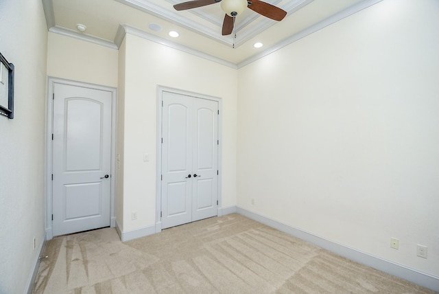 unfurnished bedroom with ceiling fan, a tray ceiling, light carpet, a closet, and ornamental molding