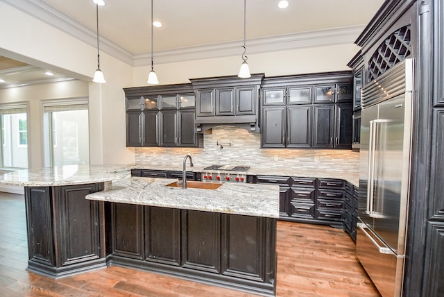 kitchen with hardwood / wood-style floors, light stone countertops, hanging light fixtures, and appliances with stainless steel finishes