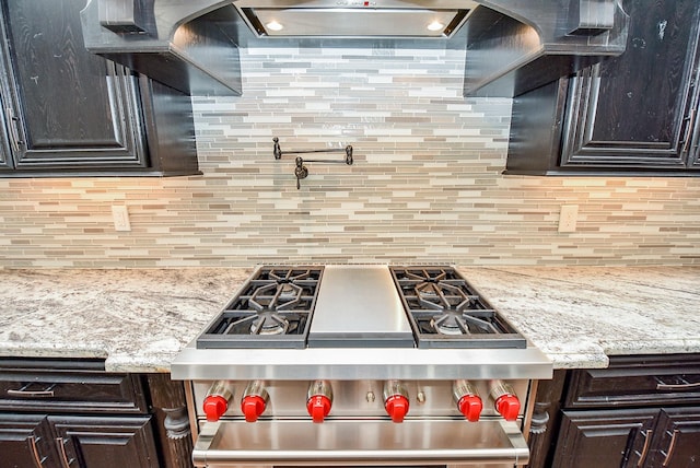 kitchen with decorative backsplash, stove, light stone counters, and dark brown cabinets