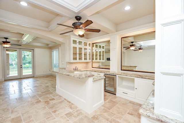 kitchen featuring french doors, decorative backsplash, light stone countertops, beam ceiling, and beverage cooler