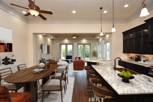 kitchen with dark hardwood / wood-style flooring, a center island with sink, pendant lighting, and ornamental molding