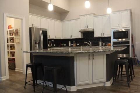 kitchen with a breakfast bar, white cabinetry, stainless steel appliances, and a kitchen island with sink