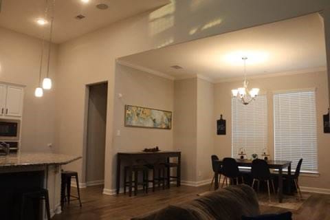 living room with dark hardwood / wood-style floors, crown molding, and a chandelier