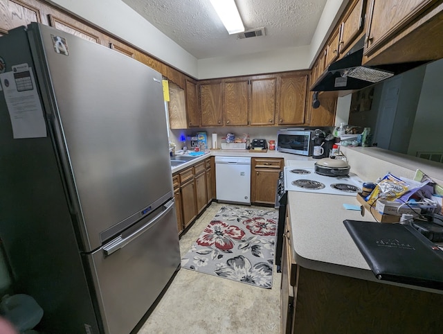 kitchen featuring stainless steel appliances, wall chimney exhaust hood, and a textured ceiling