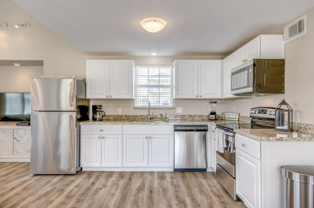 23171 Buena, Galveston, TX 77555 - kitchen with light stone countertops, sink, appliances with stainless steel finishes, white cabinets, and light wood-type flooring
