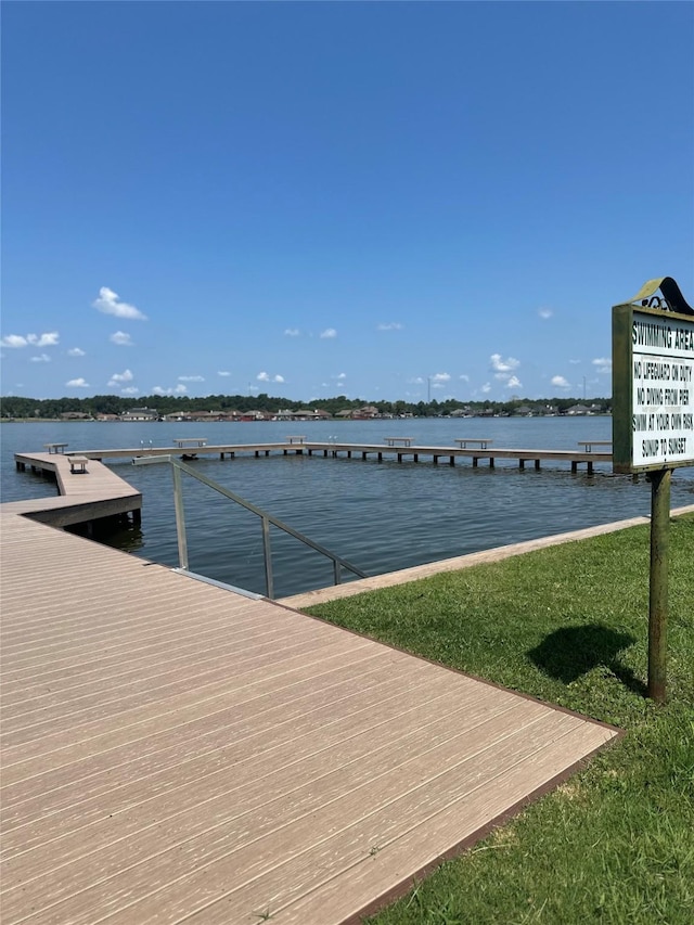 view of dock with a lawn and a water view