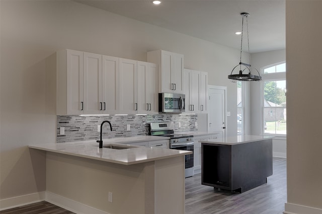 kitchen featuring a center island, sink, stainless steel appliances, decorative light fixtures, and white cabinets