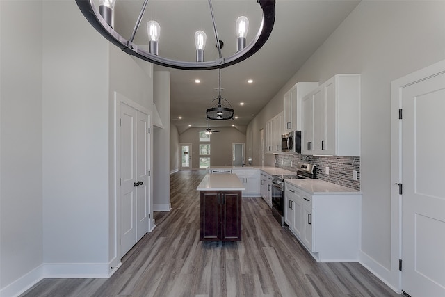 kitchen featuring appliances with stainless steel finishes, ceiling fan with notable chandelier, white cabinetry, and a kitchen island