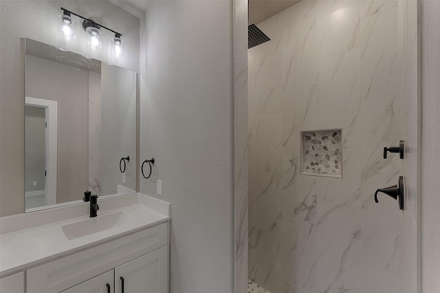 bathroom with a tile shower and vanity