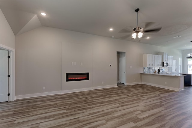 unfurnished living room featuring ceiling fan, hardwood / wood-style floors, and lofted ceiling