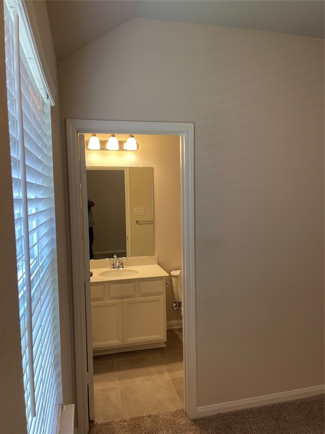 bathroom with tile floors, lofted ceiling, vanity, and toilet