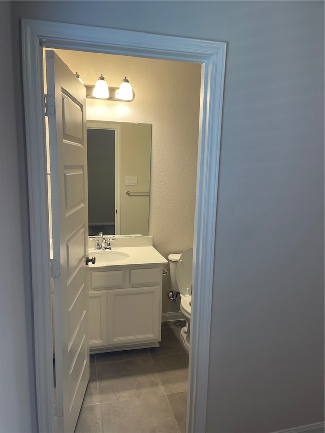 bathroom with tile flooring, vanity, and toilet