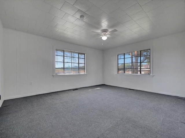 carpeted empty room with ceiling fan and a wealth of natural light