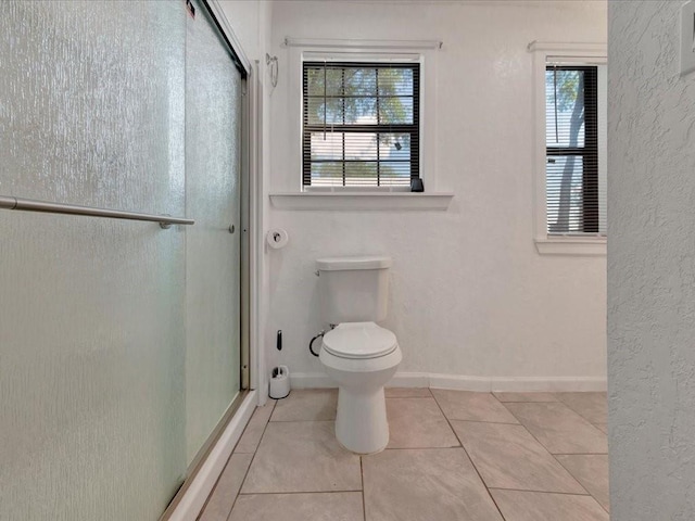 bathroom with tile patterned flooring, an enclosed shower, and toilet