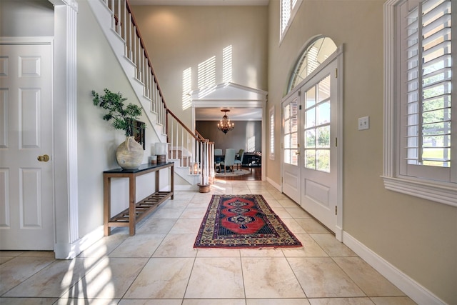 foyer entrance with a chandelier, light tile patterned floors, french doors, and a wealth of natural light