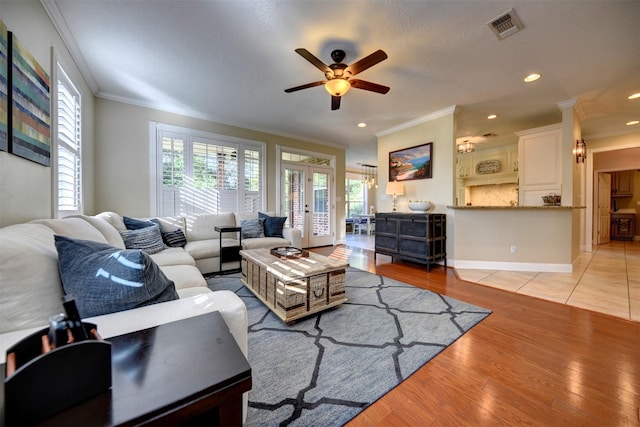 living room featuring ceiling fan, light wood-type flooring, crown molding, and french doors