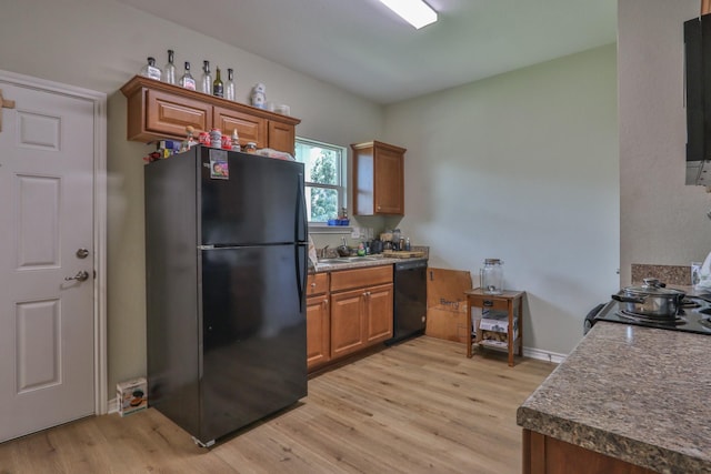 kitchen featuring black appliances, light wood-type flooring, and sink