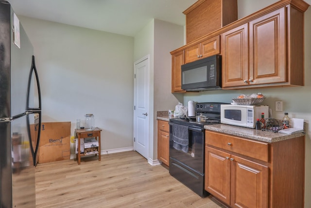 kitchen featuring light wood-type flooring and black appliances