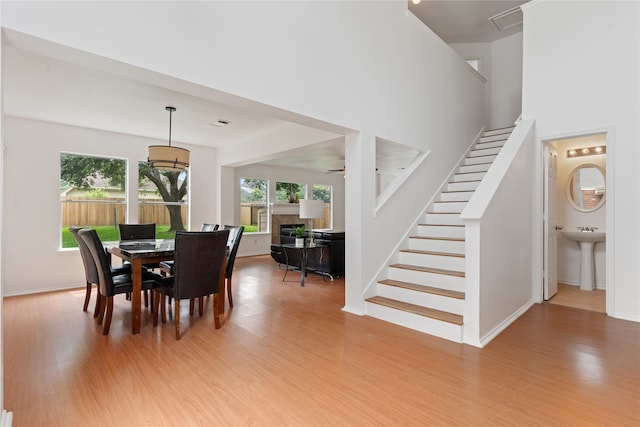 dining area with a high ceiling, sink, and light hardwood / wood-style flooring