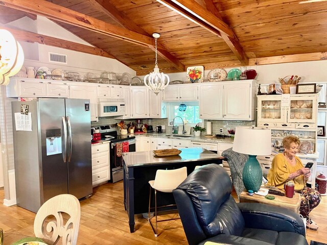 kitchen featuring wood ceiling, appliances with stainless steel finishes, light wood-type flooring, and tasteful backsplash