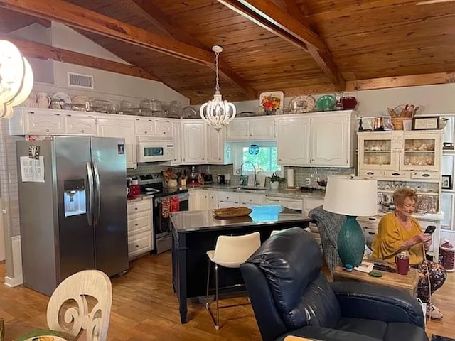 kitchen with white cabinetry, tasteful backsplash, lofted ceiling with beams, appliances with stainless steel finishes, and wood ceiling