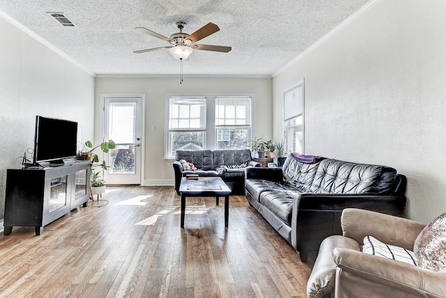 living room featuring ceiling fan, light hardwood / wood-style flooring, crown molding, and a textured ceiling