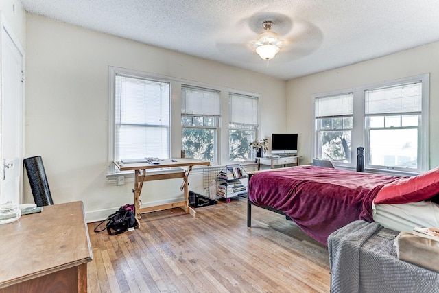 bedroom with ceiling fan, light hardwood / wood-style floors, and a textured ceiling