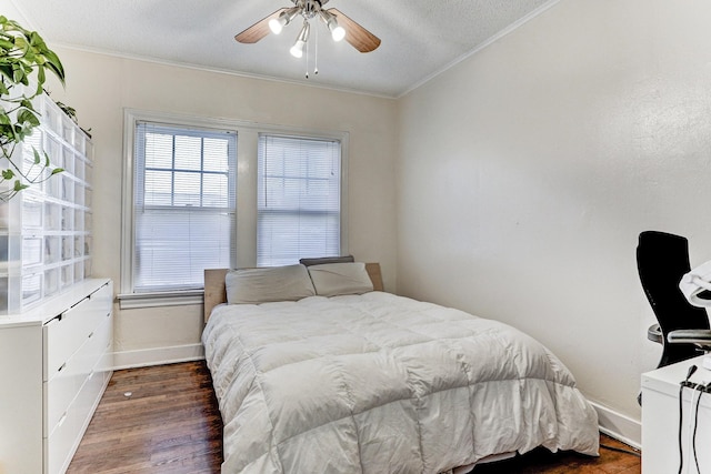 bedroom with a textured ceiling, dark wood-type flooring, ceiling fan, and ornamental molding