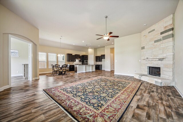 living room featuring a fireplace, dark wood-type flooring, and ceiling fan with notable chandelier