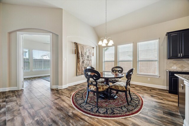 dining area with a notable chandelier, high vaulted ceiling, and dark hardwood / wood-style flooring