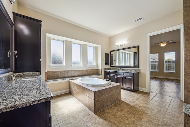 bathroom featuring tile flooring, a relaxing tiled bath, vanity, and ceiling fan