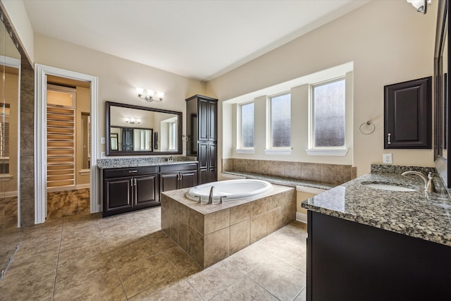 bathroom with tile floors, a relaxing tiled bath, and double sink vanity