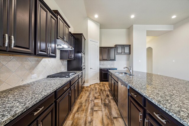 kitchen featuring dark hardwood / wood-style flooring, stainless steel appliances, tasteful backsplash, light stone countertops, and sink