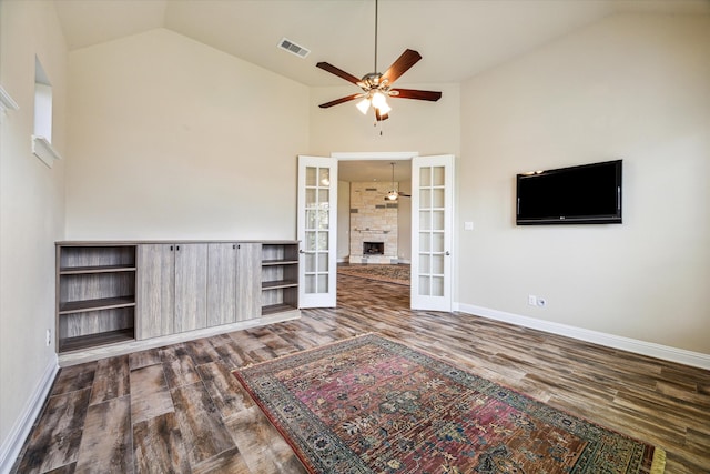 unfurnished living room with high vaulted ceiling, ceiling fan, french doors, and dark wood-type flooring