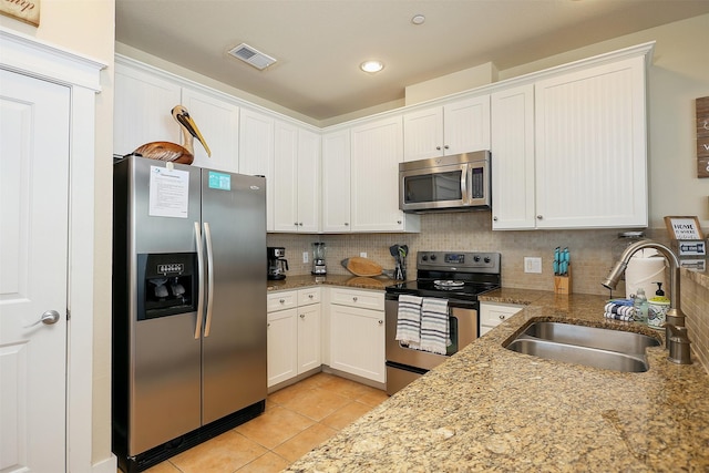 kitchen with white cabinetry, sink, light stone countertops, tasteful backsplash, and appliances with stainless steel finishes