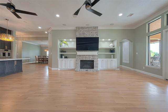 unfurnished living room with built in features, ceiling fan with notable chandelier, and a fireplace